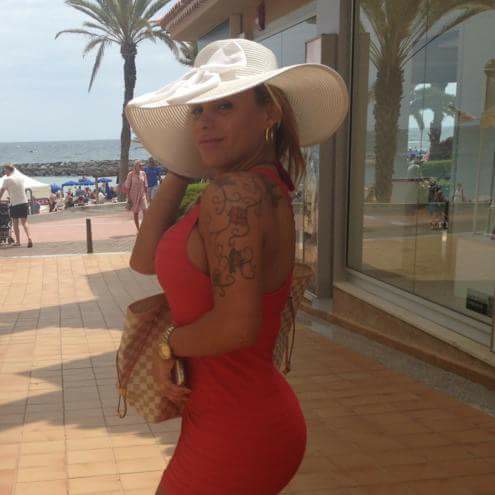 Aria in a red dress and hat near the coast
