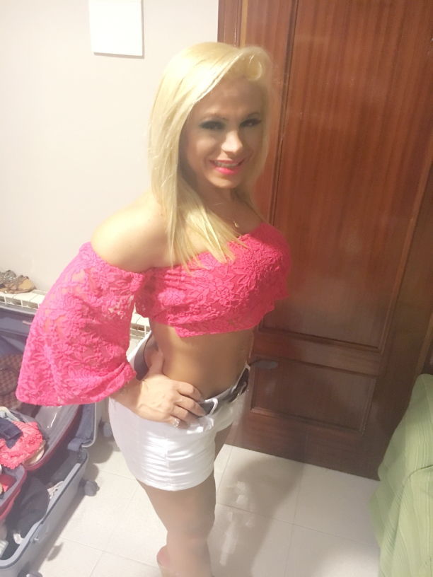 Aria in a pink top and white skirt