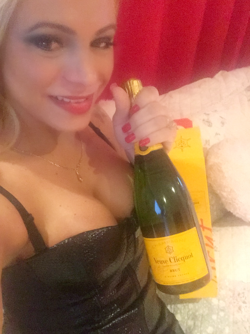 Aria in a black evening dress holding a champagne bottle